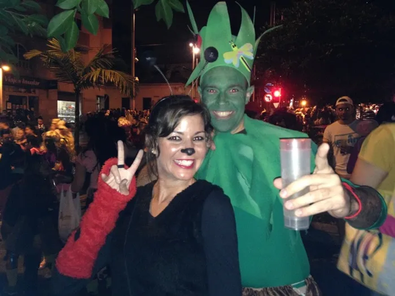 Pareja disfrazada en carnaval, rodeada de gente y ambiente festivo.