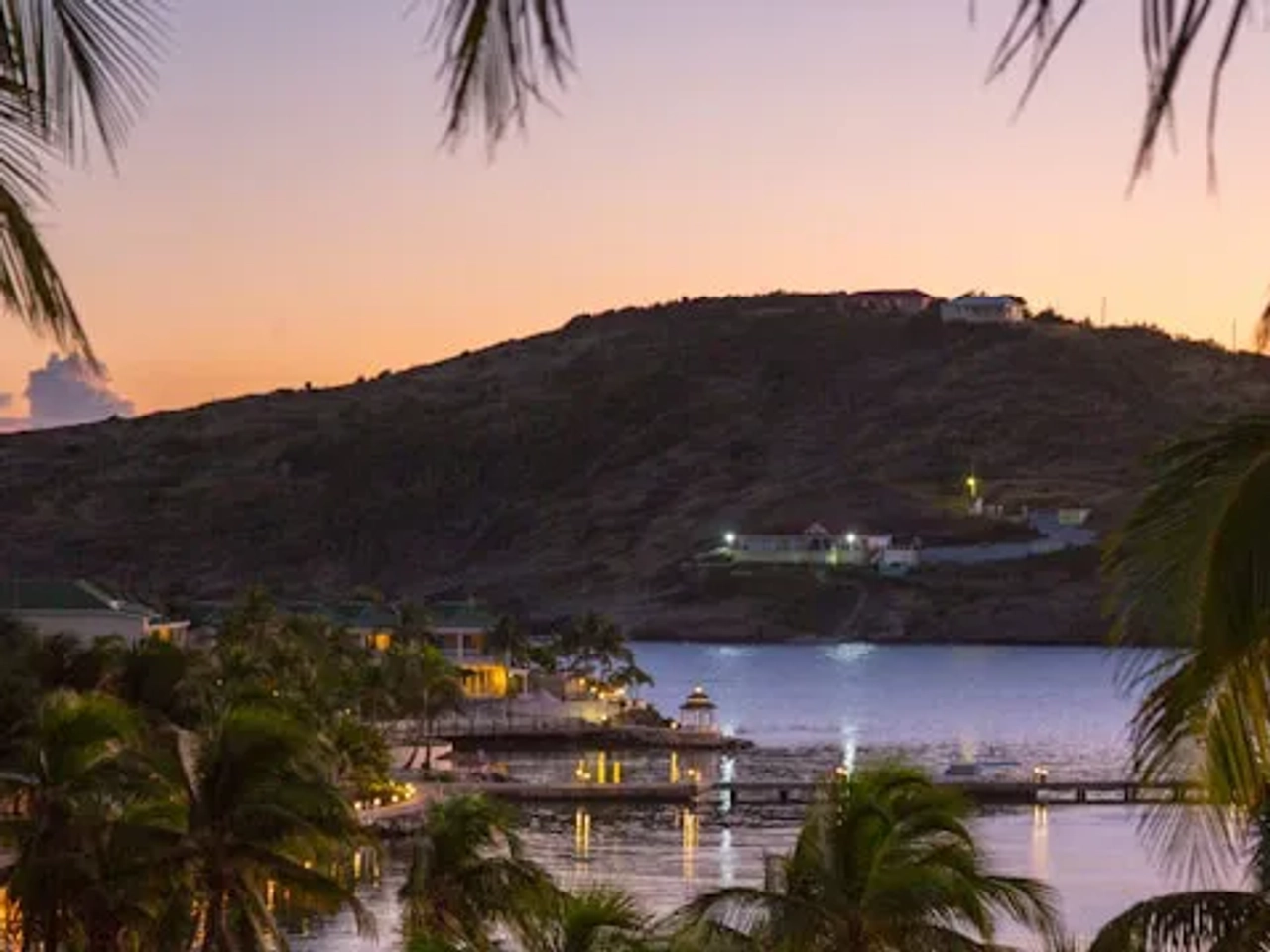 vista de antigua ao por do sol com barcos e plameiras e luzes da cidade