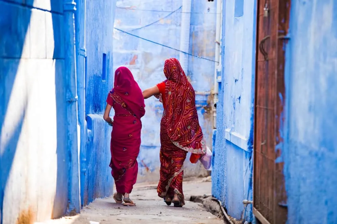 duas mulheres indianas caminham numa rua estreita