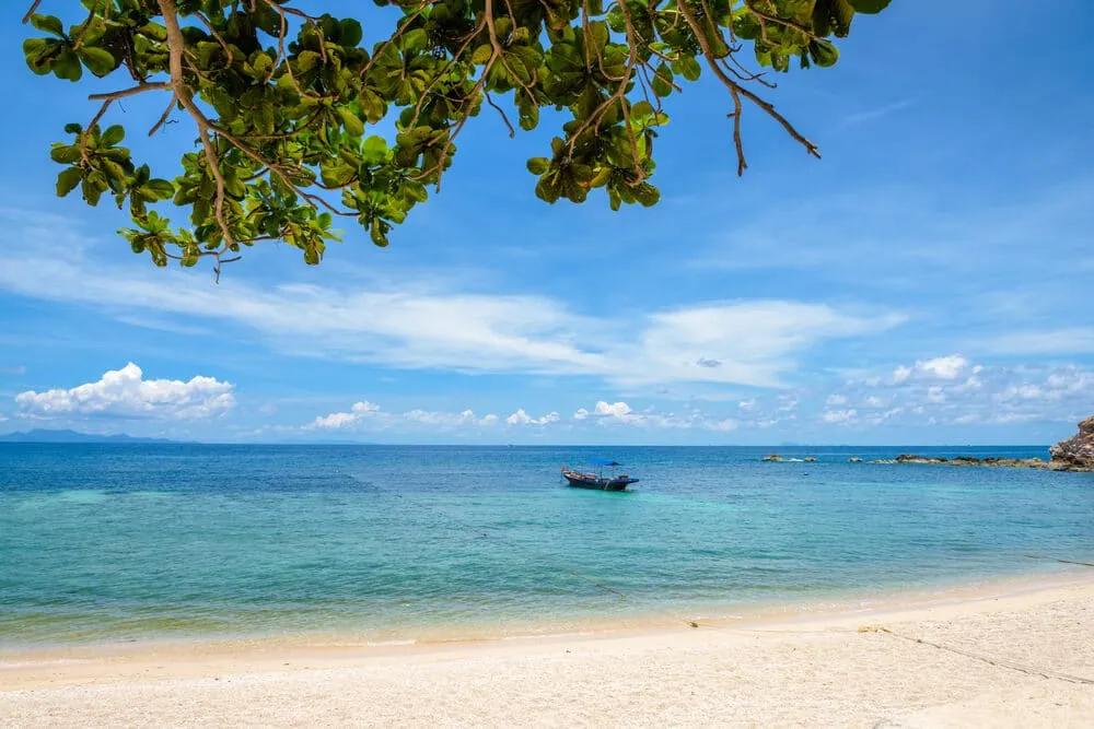 areal, mar azul e barco à deriva