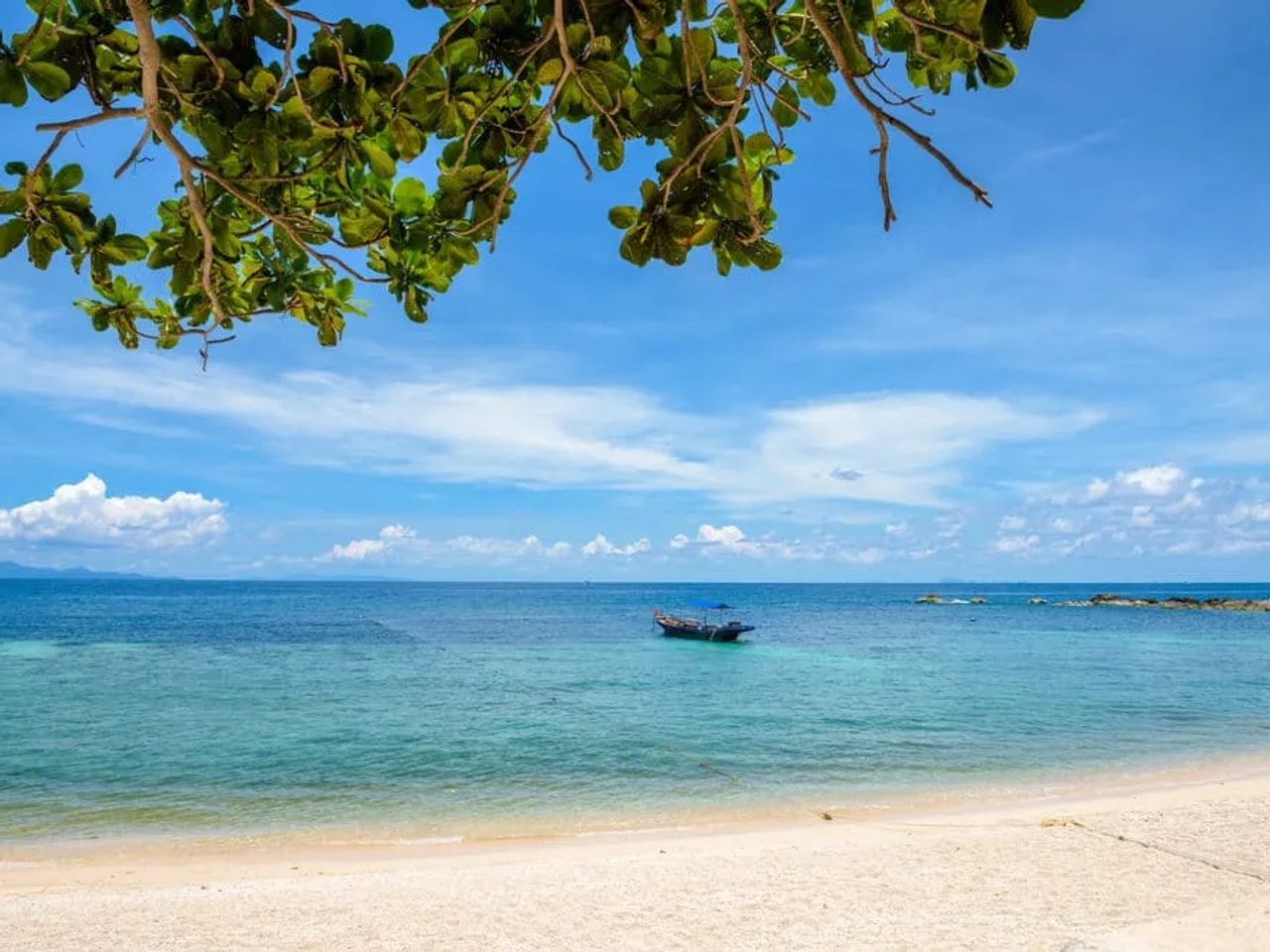 areal, mar azul e barco à deriva