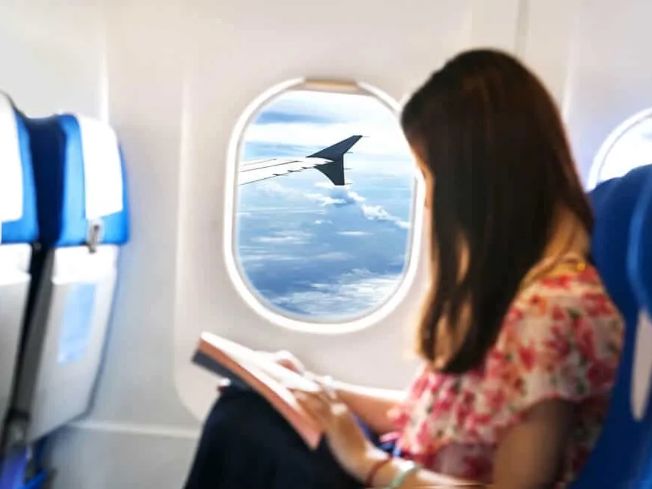 mulher sentada na janela do aviao a ler