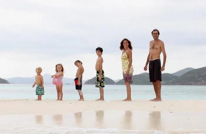 Familia de pie en la playa, disfrutando del mar y la arena.