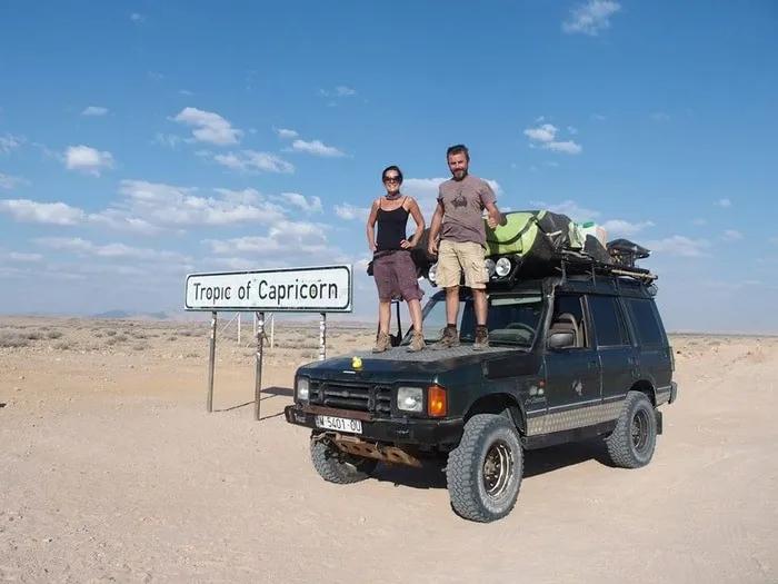 Dos personas sobre un vehículo en el Trópico de Capricornio, paisaje desértico.