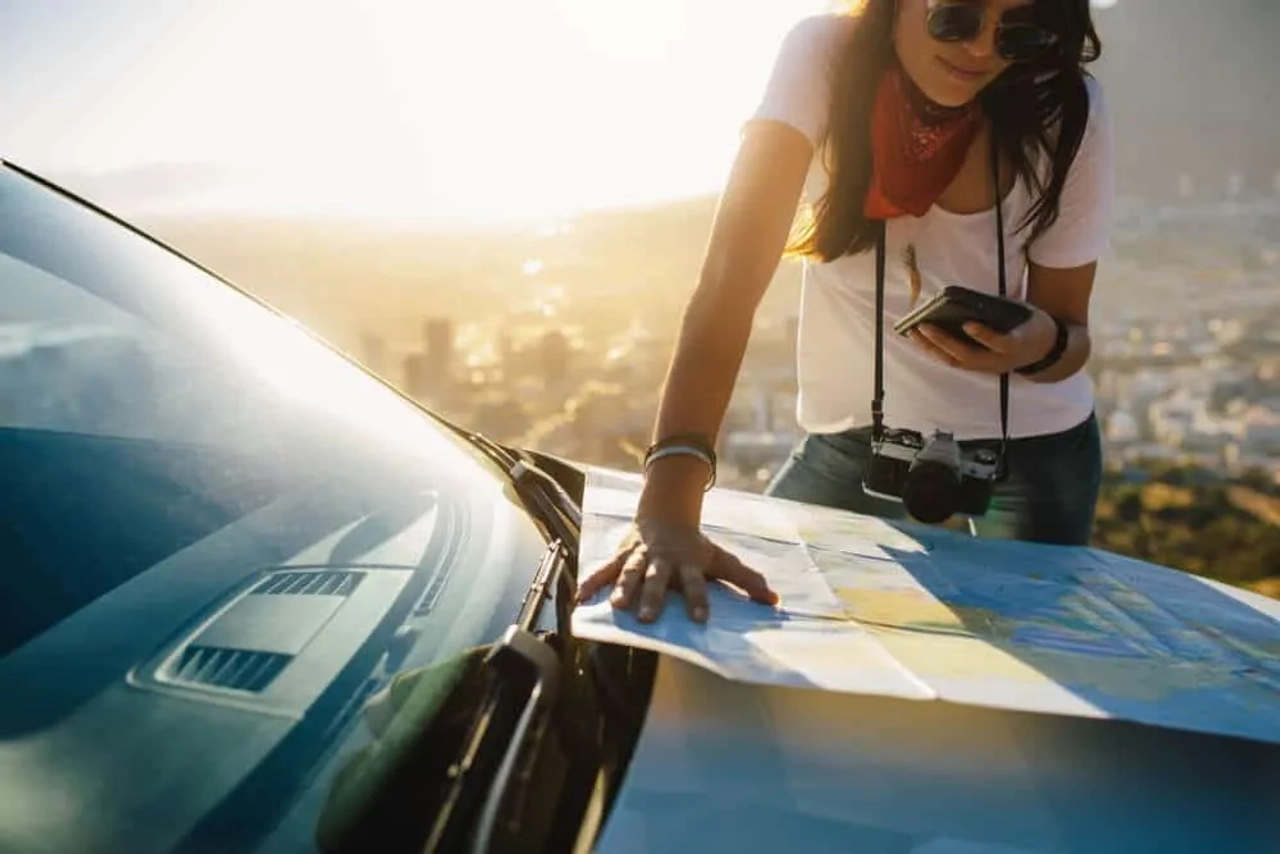 mulher a consultar um mapa em cima de um carro