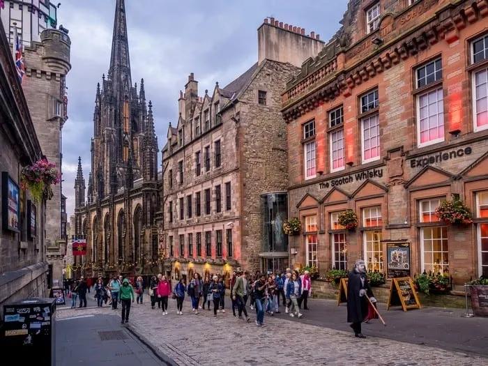 Rua movimentada em Edimburgo, com edifícios históricos e a Scotch Whisky Experience.