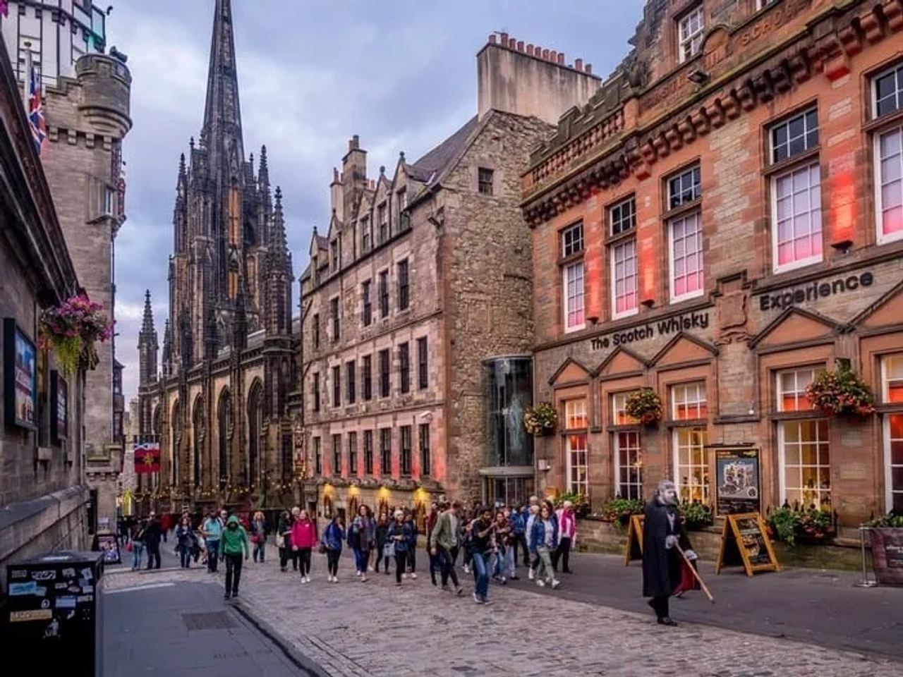 Rua movimentada em Edimburgo, com edifícios históricos e a Scotch Whisky Experience.