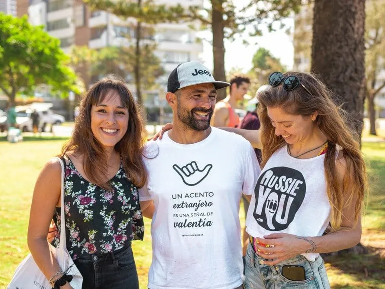 Tres personas sonrientes en un parque, conversando y disfrutando del momento.