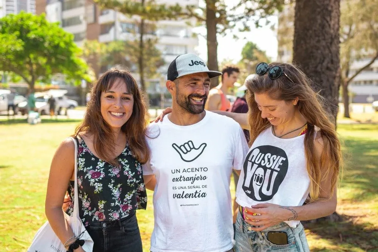 Tres personas sonrientes en un parque, conversando y disfrutando del momento.