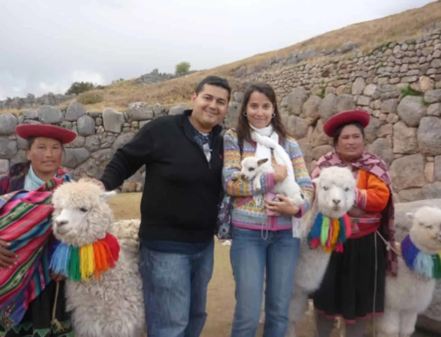 Grupo de personas posando con llamas en un paisaje andino.