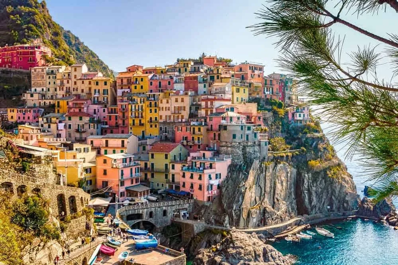 Vista de Manarola, em Cinque Terre, com casas coloridas sobre a falésia e o mar ao fundo.