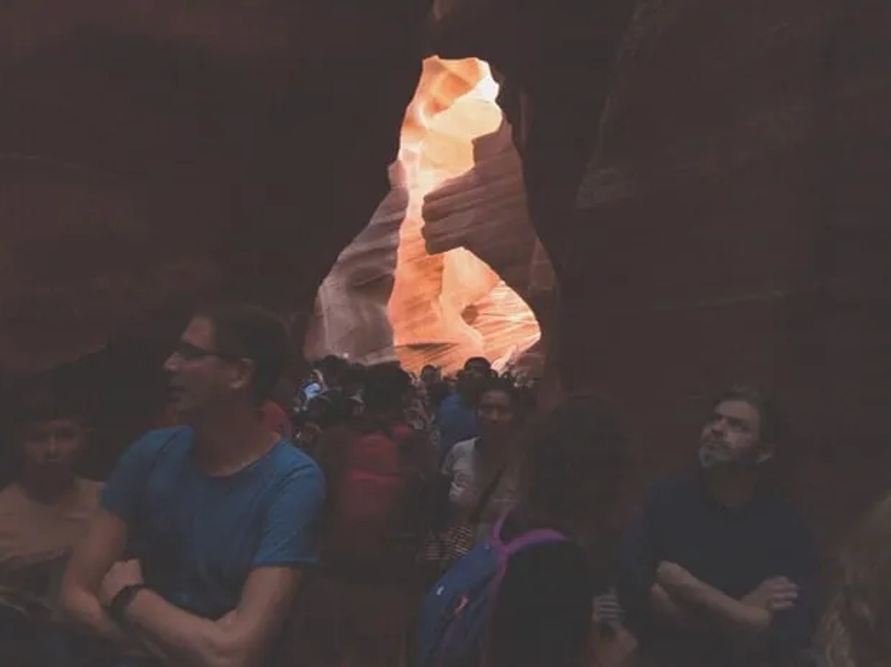 Grupo de personas en un cañón con formaciones rocosas iluminadas.