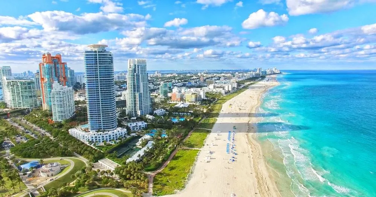 Vista aérea de Miami Beach, nos Estados Unidos, com praia, mar azul e edifícios junto à costa.