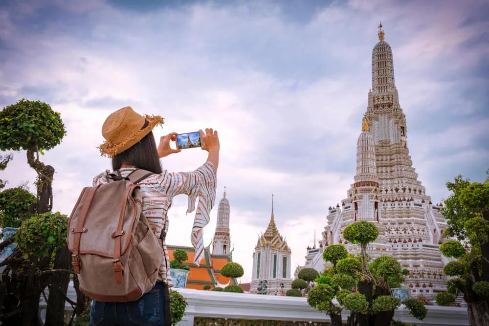 mulher tira fotos a um templo na tailandia