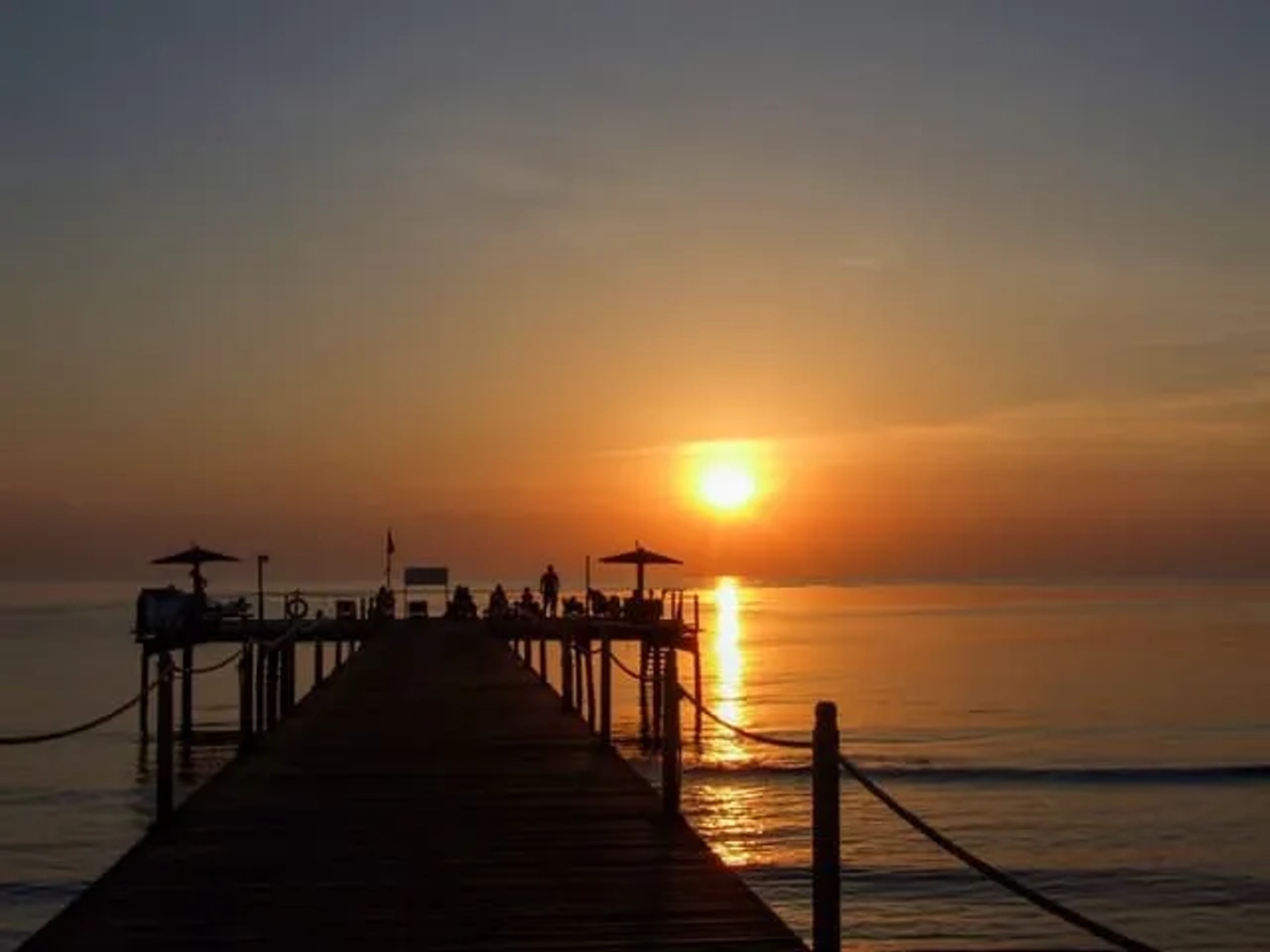 Tramonto sul mare con pontile e mare calmo con riflessi del sole a Marsa Alam, Egitto
