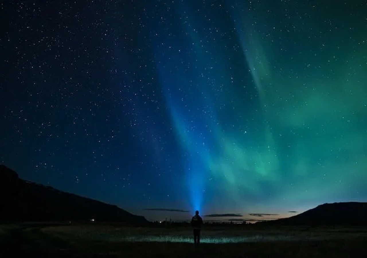 pessoa a ver auroras boreais na islândia azuis e verdes