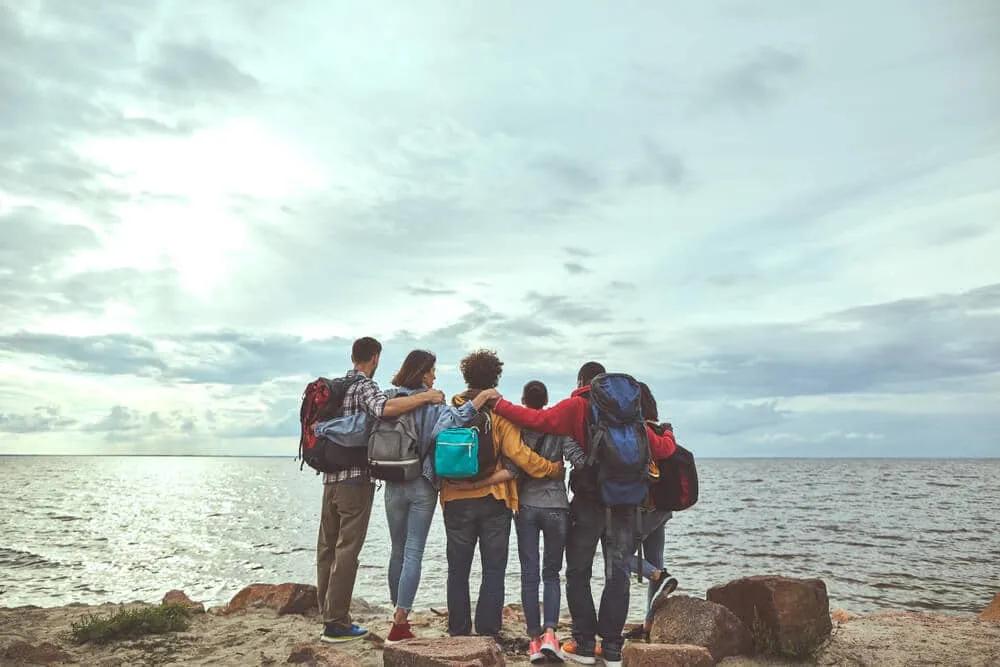 grupo de amigos tira foto de costas enquanto observa o mar