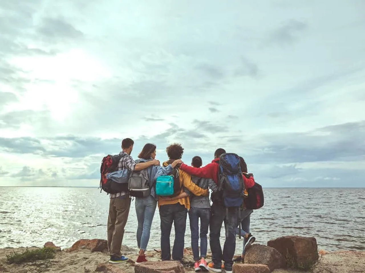 grupo de amigos tira foto de costas enquanto observa o mar