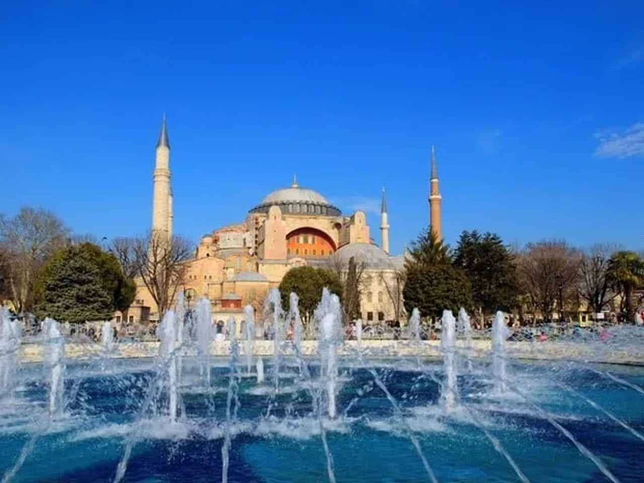 Vista da Hagia Sophia com fontes em primeiro plano e céu azul.
