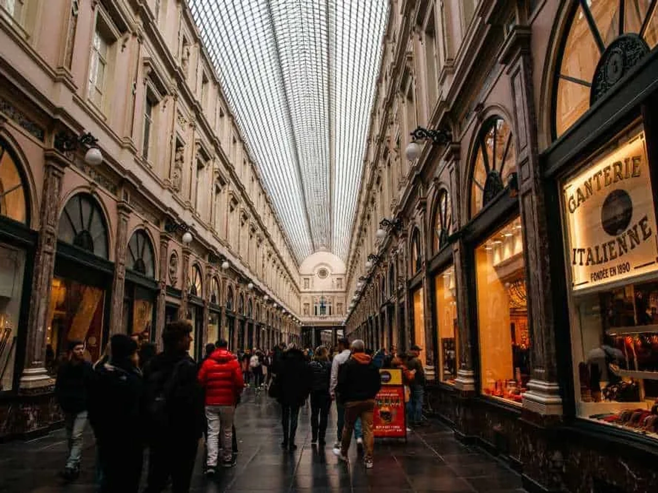 Pasillo comercial en Bruselas con tiendas y un techo de vidrio.