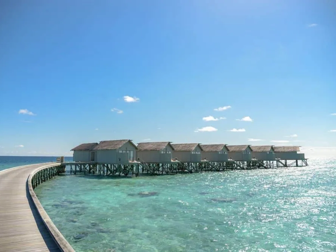Cabañas sobre el agua en Maldivas, conectadas por un camino de madera.