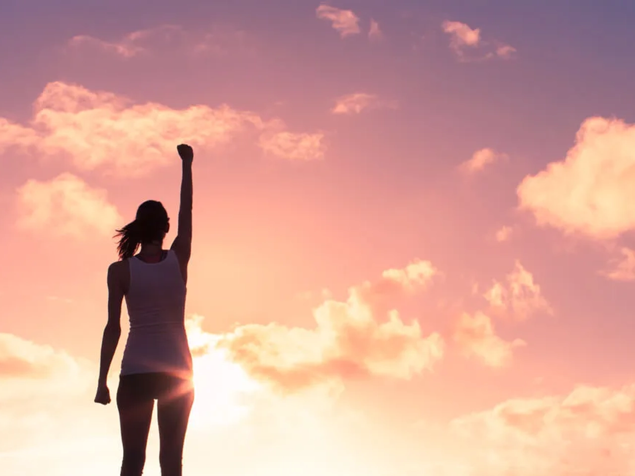 mulher de braço levantado ao atardecer