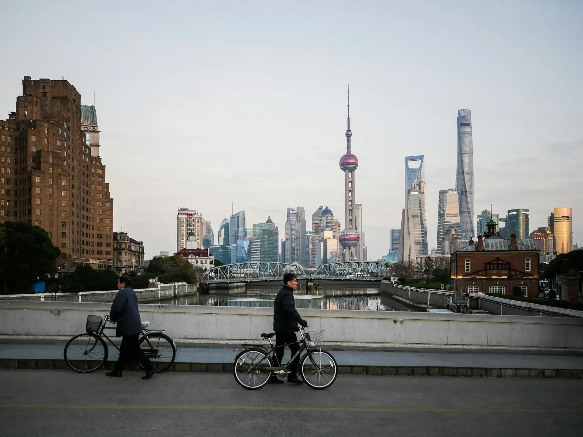 Ciclisti e traffico urbano davanti allo skyline di Shanghai durante un viaggio in Cina.