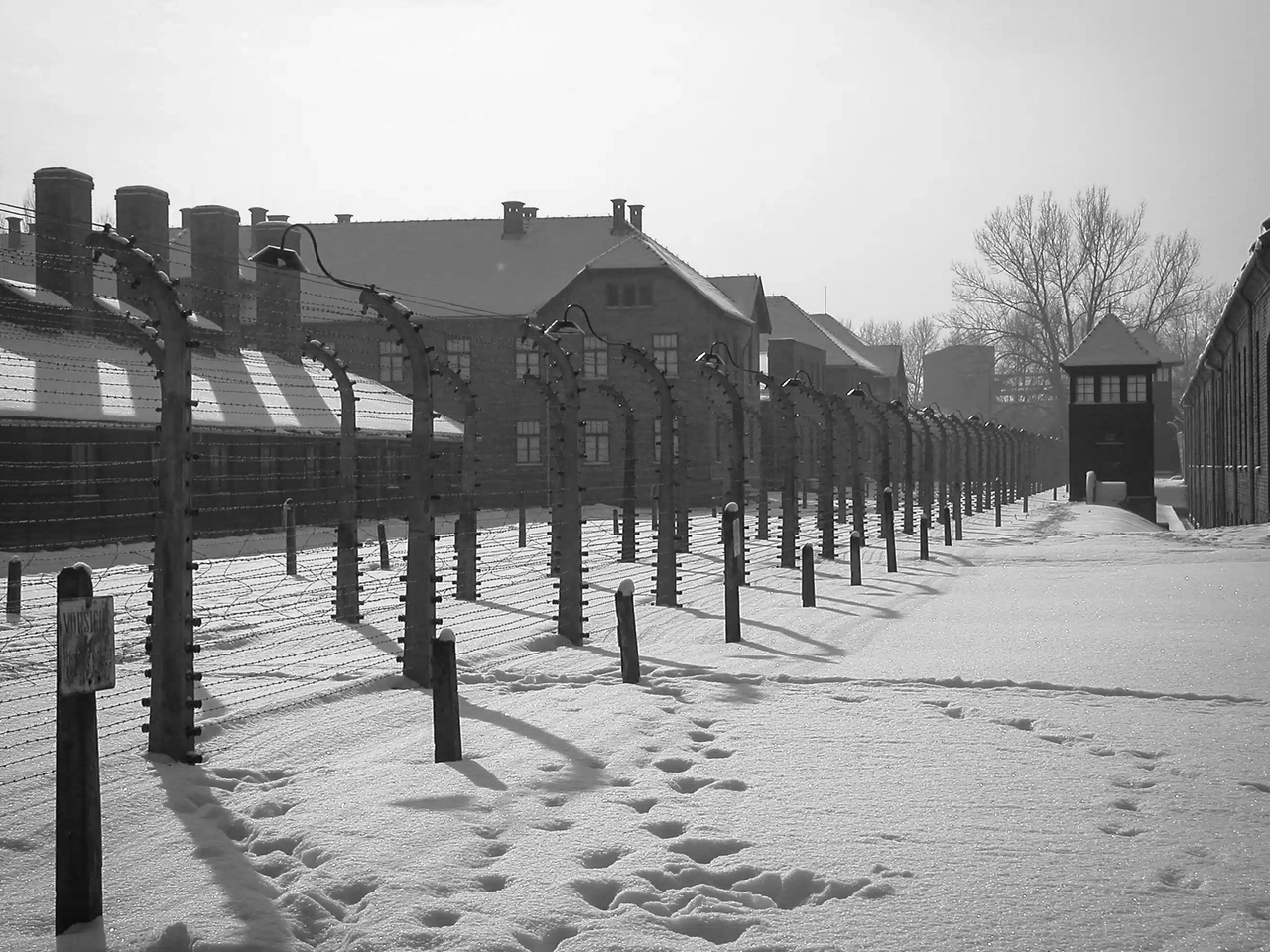 Memorial de Auschwitz-Birkenau, perto de Cracóvia, com neve e barracões históricos.
