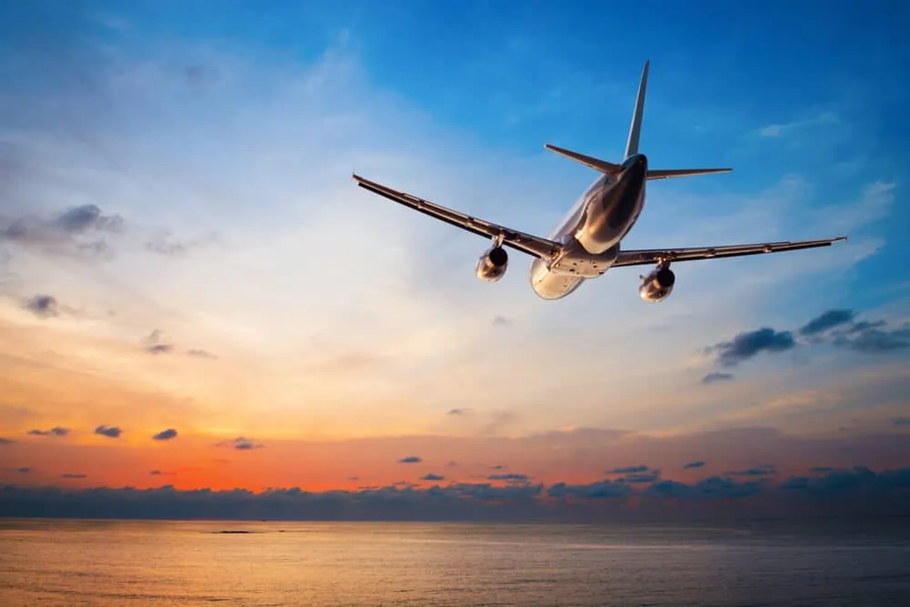 aviao voa em direçao ao por do sol