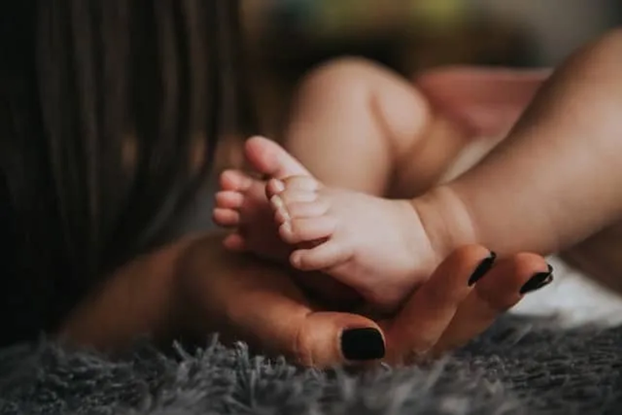 pés de criança a serem segurados por mãos de adulto