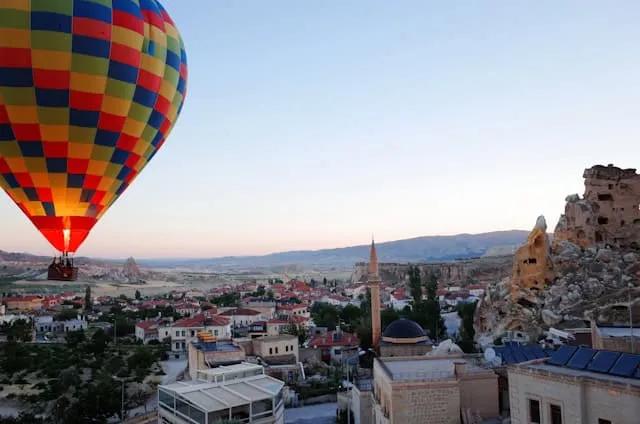 balão de ar quente colorido com pessoas lá dentro a sobrevoar a capadócia na turquia