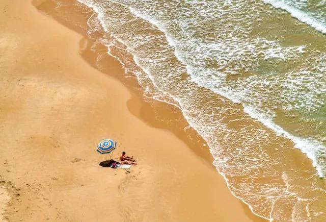 duas pessoas estendidas na areia junto a um guarda sol numa praia em Agrigento na sicilia
