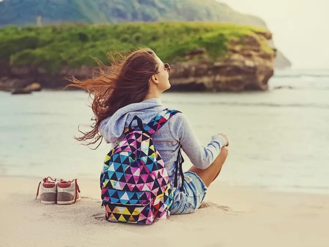 mulher desfruta sozinha sentada na praia