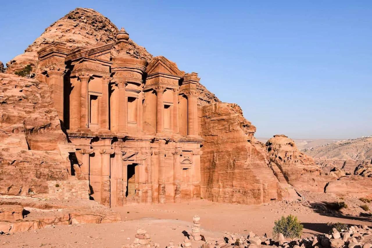 Templo de Petra, uma impressionante construção esculpida na rocha, cercada por montanhas.