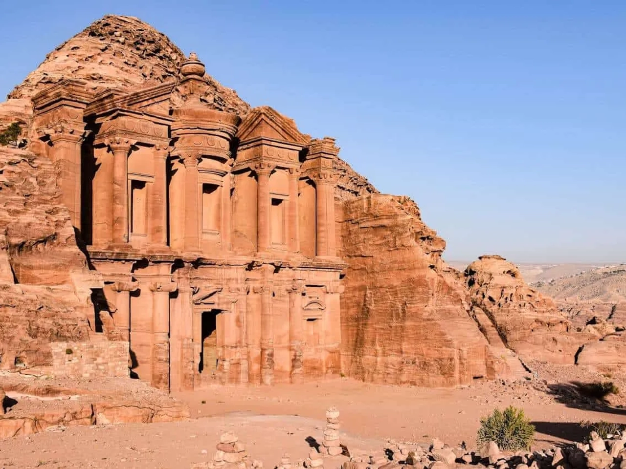 Templo de Petra, uma impressionante construção esculpida na rocha, cercada por montanhas.