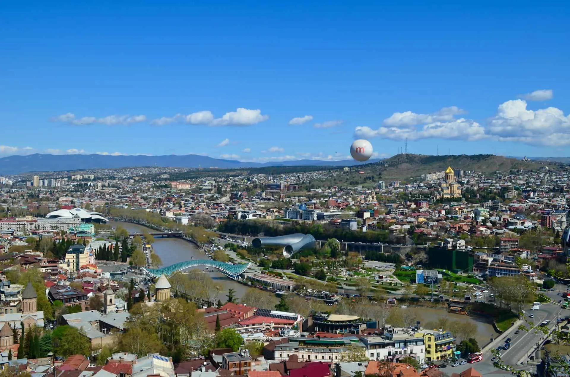 Vista panorâmica de Tbilisi, Geórgia, com o rio e arquitetura diversificada.
