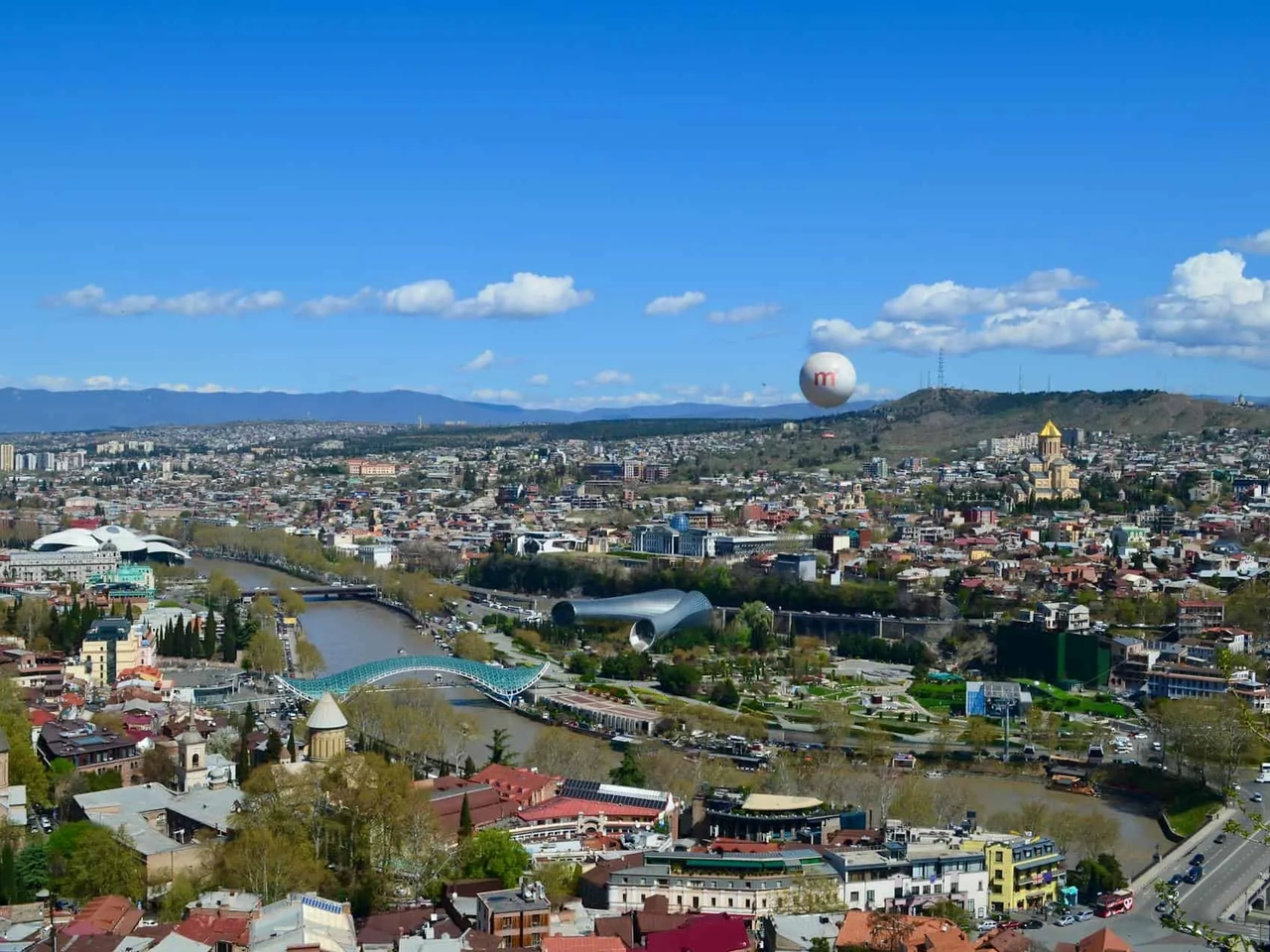 Vista panorâmica de Tbilisi, Geórgia, com o rio e arquitetura diversificada.