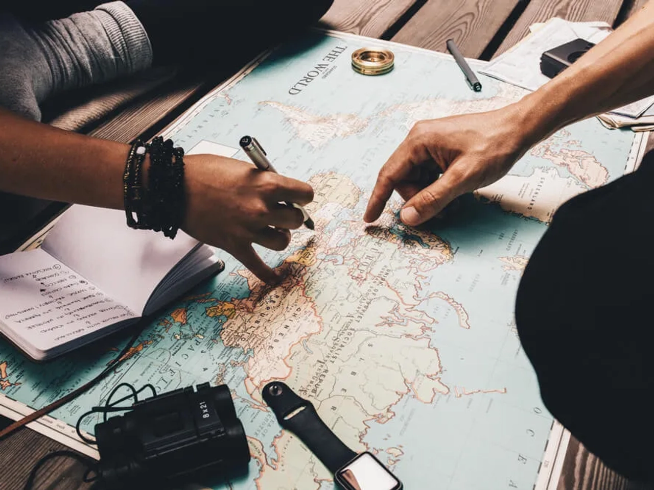 dois amigos planeiam uma viagem com um mapa mundo