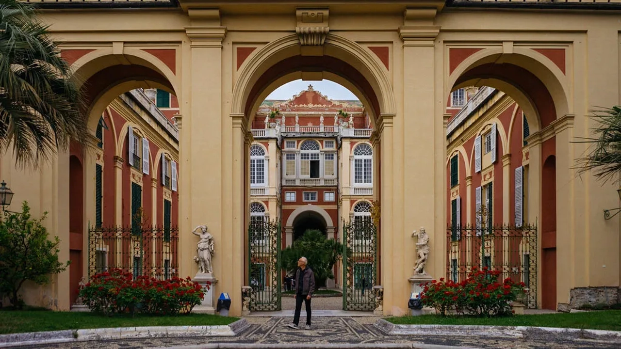 Arcos imponentes em um palácio histórico com jardins e estátuas.
