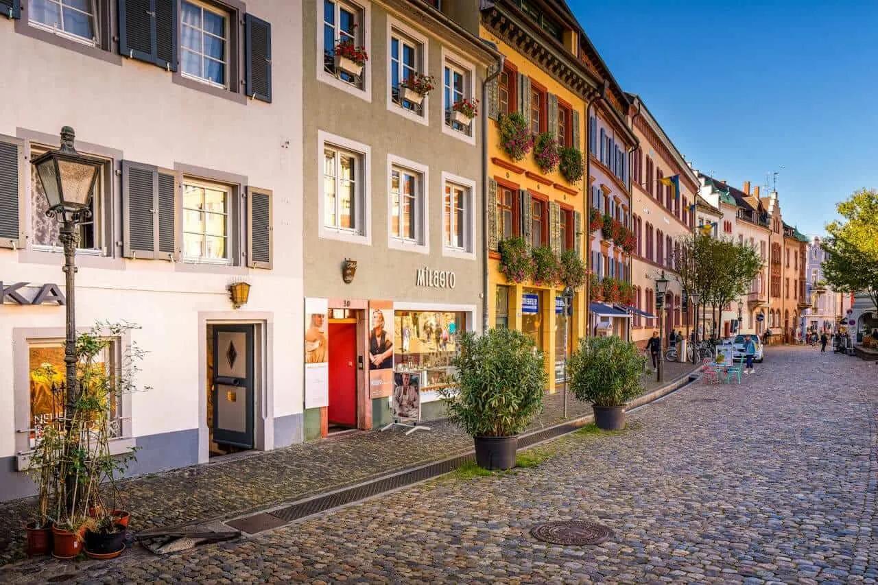 Rua charmosa com edifícios coloridos e lojas, típica de cidades alemãs.
