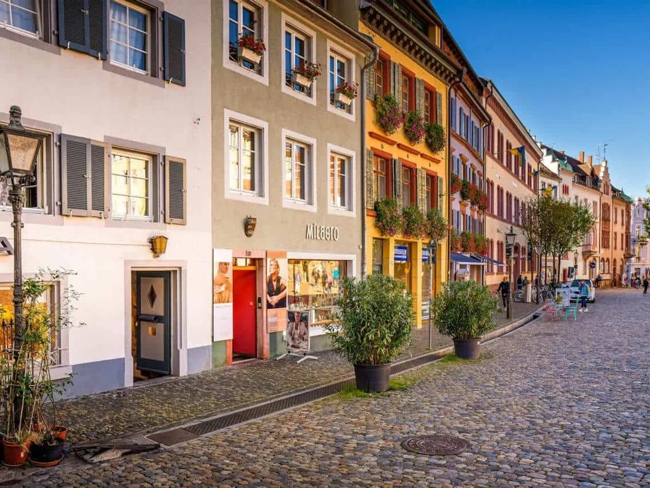 Rua charmosa com edifícios coloridos e lojas, típica de cidades alemãs.