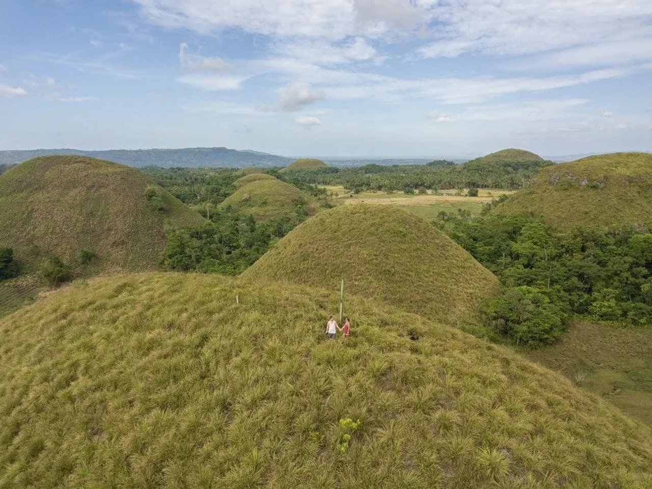 Dos personas en una colina rodeada de montañas verdes y paisaje natural.