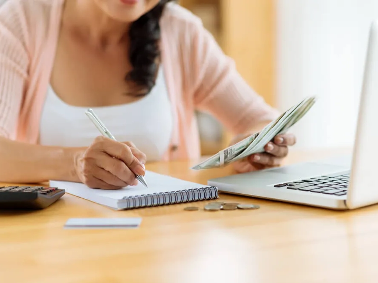 mulher com computador faz contas numa folha