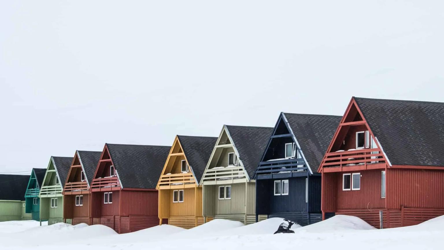 Casas coloridas em Svalbard, Noruega, cercadas por neve em um ambiente ártico.
