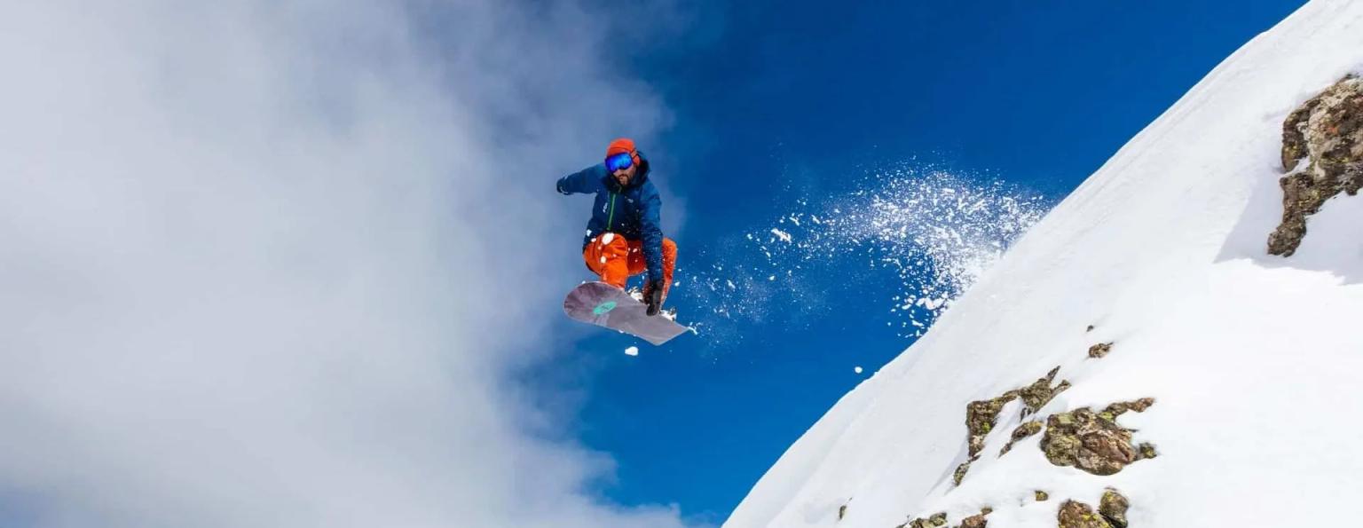 Um snowboarder salta por cima de um penhasco em Montgenèvre, França