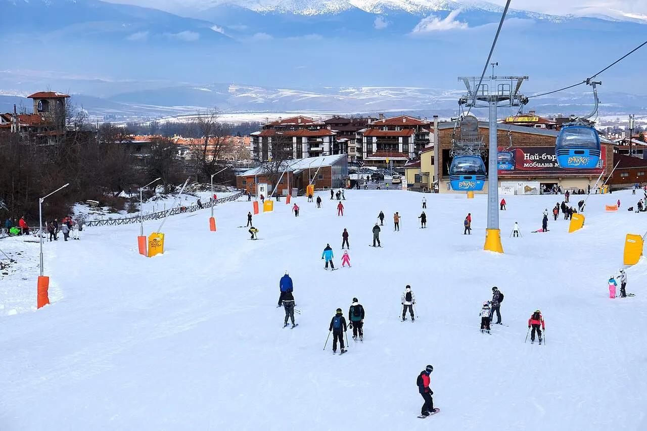 Pista de esqui movimentada com esquiadores e teleféricos ao fundo.