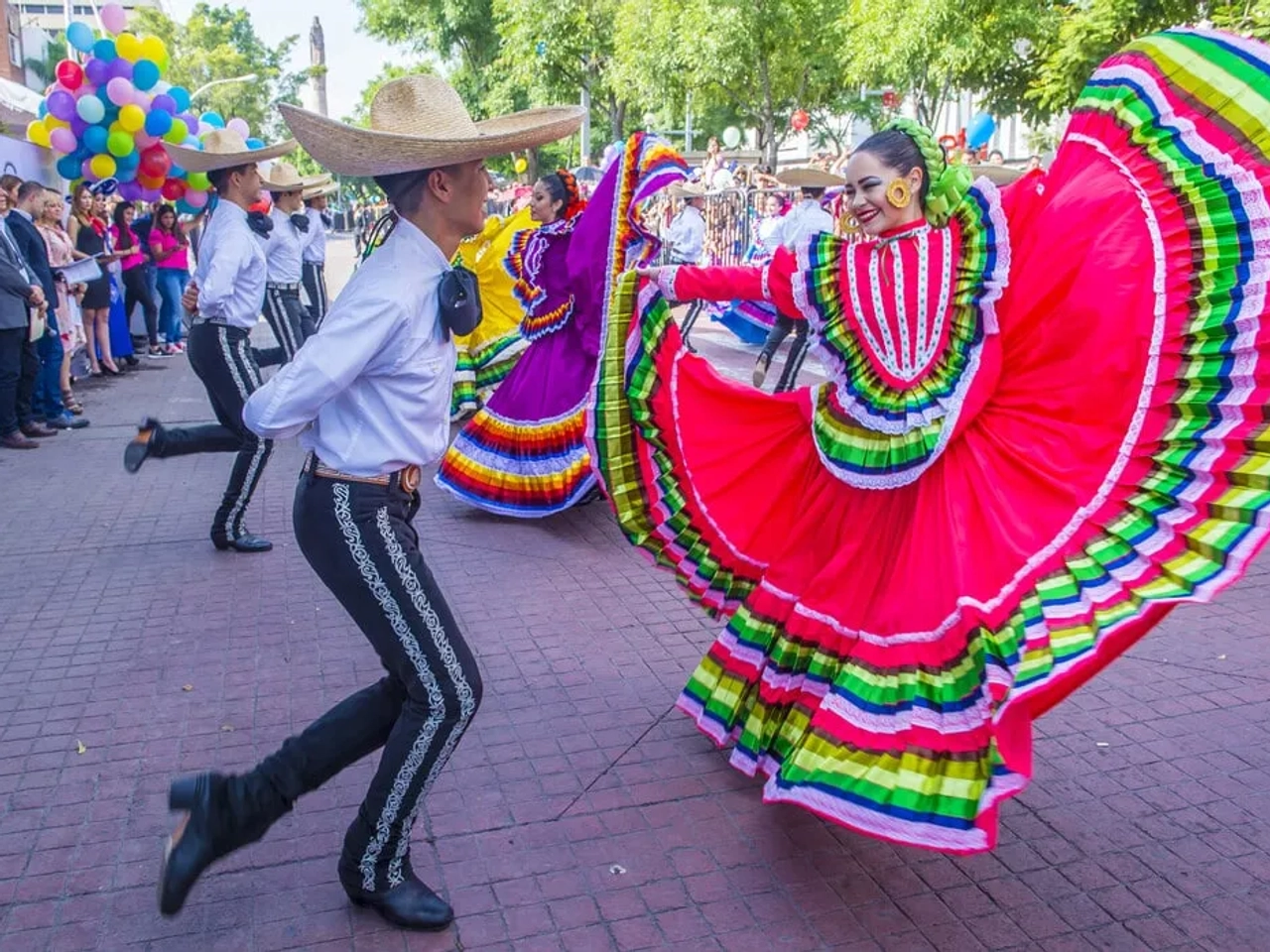 pessoas a dançar nas ruas do México com trajes coloridos