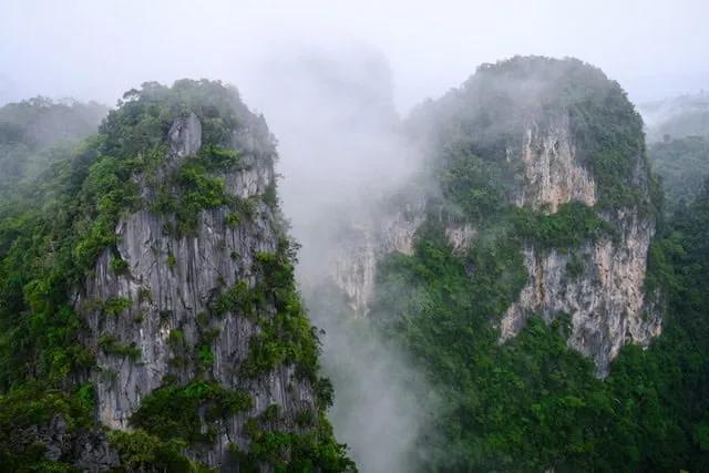 montanhas muito altas com árvores em cima e nevoeiro no Wat Tham Suea em Kanchanaburi 