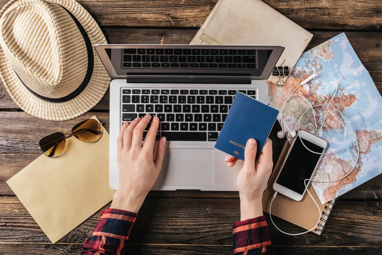 pessoa com passaporte na mao e a mexer no computador