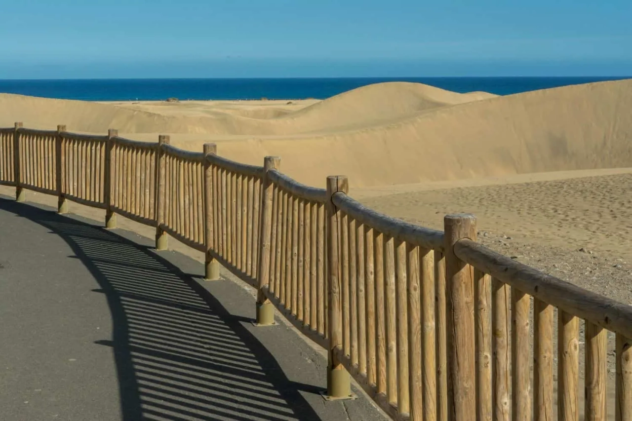 Caminho de madeira com vista para dunas e mar nas Ilhas Canárias.